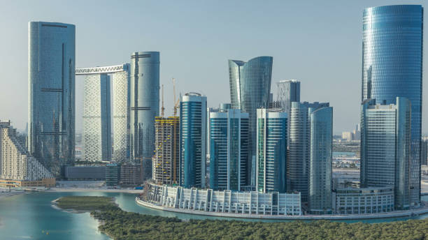 Buildings on Al Reem island in Abu Dhabi timelapse from above. Aerial cityscape of Al Reem Island at hazy morning, showing the reflection on skyscrapers.